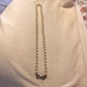 Long pearl necklace with silver bow
